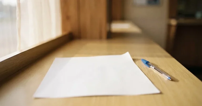 Ein leerer Papier-Wettschein ohne Aufdruck liegt neben einem Kugelschreiber auf einem hellen Tresen, weiches Seitenlicht.